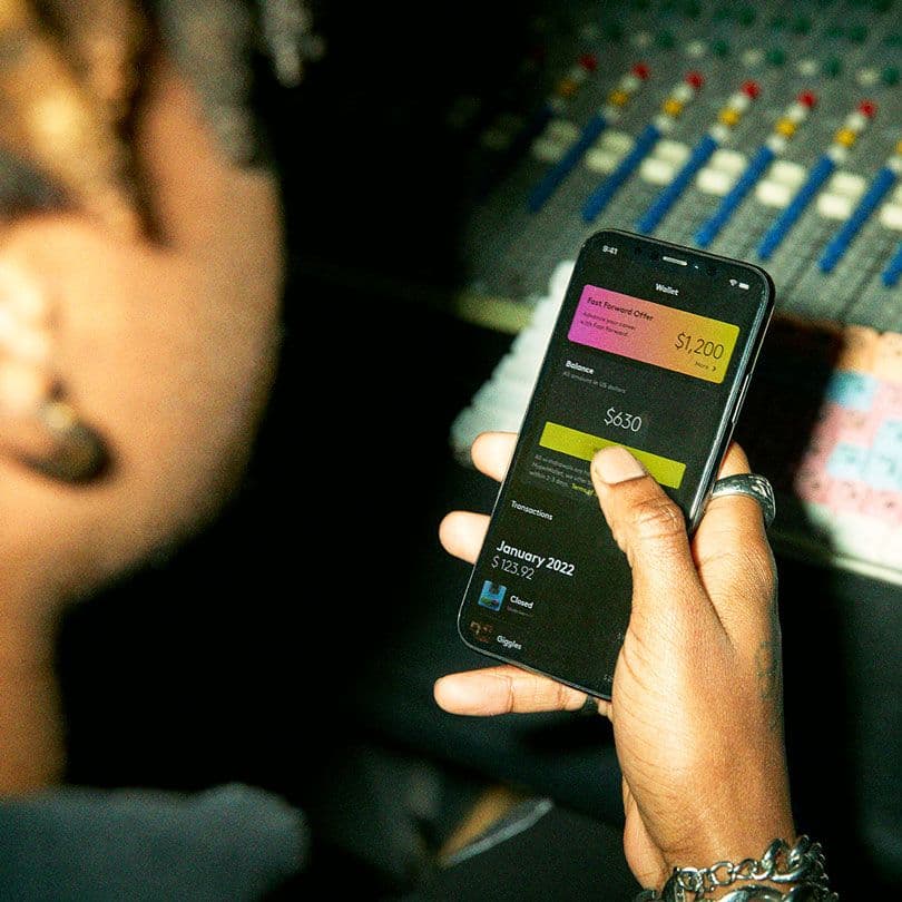 Guy holding a mobile phone showing a "Fast Forward Offer" of 1200 US dollar in the Wallet tab, inside the amuse app