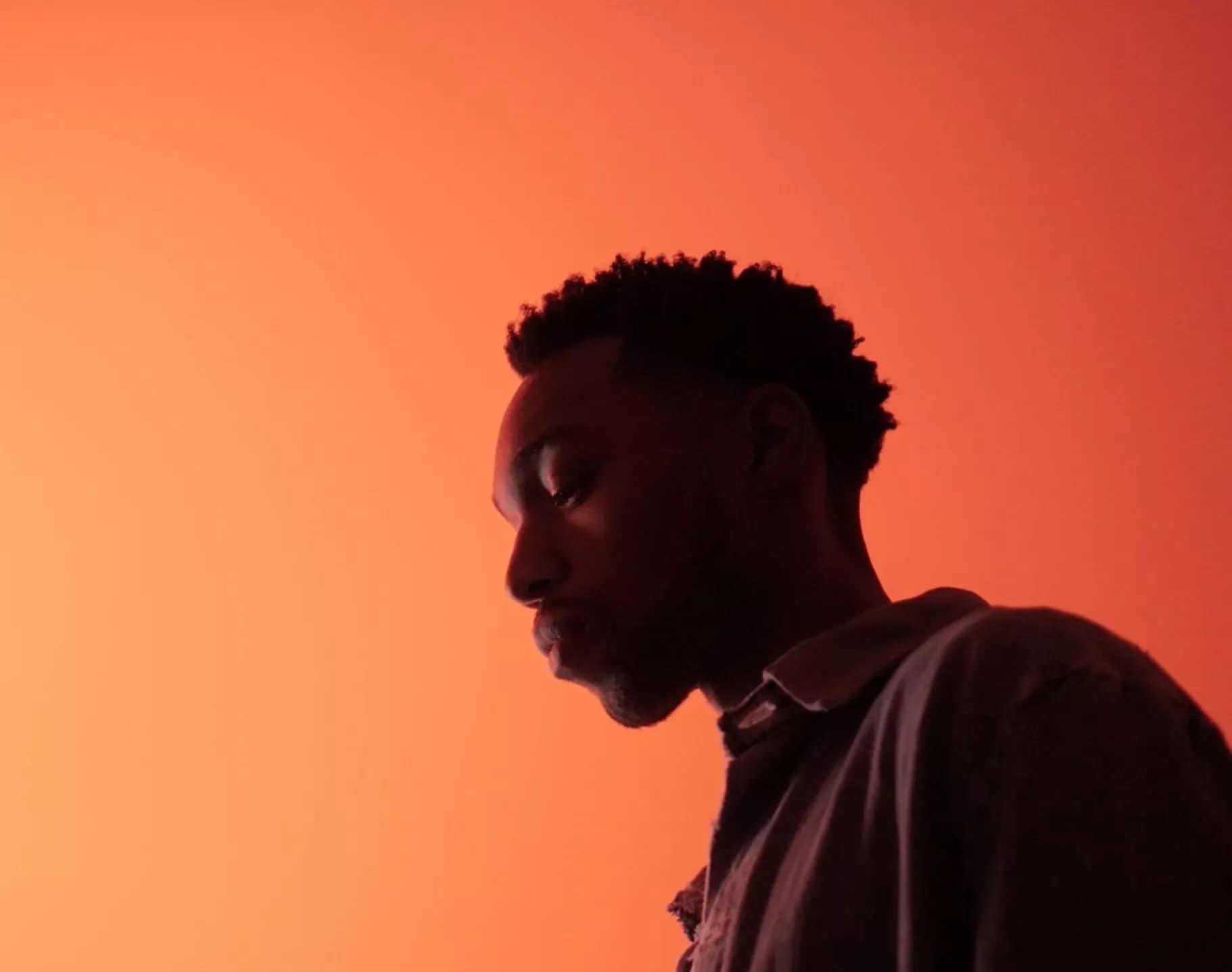 Artist Julian Bell side profile with orange background