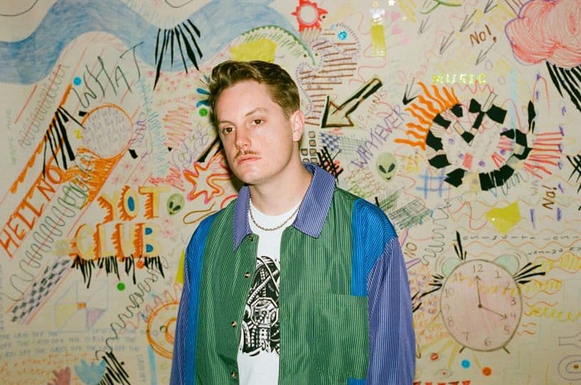 Press photo of amuse artist YotClub, against an artsy wall