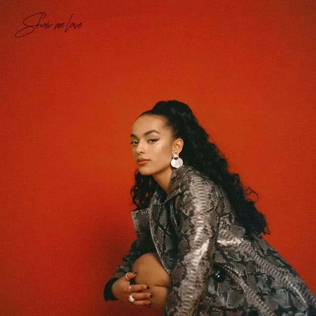 Artist Naliyah bending down in front of a red background that says "Show You Love"
