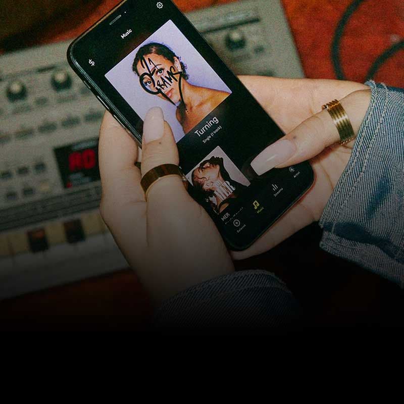 Photo showing hands holding a mobile phone, with screen showing a release/album cover in the amuse app