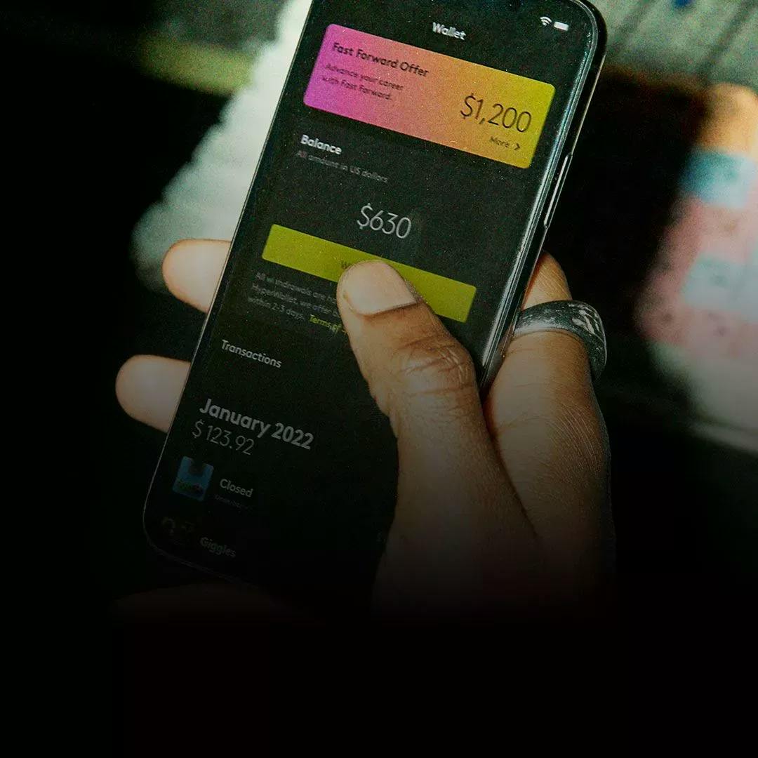 Hand holding a mobile phone showing a "Fast Forward Offer" of 1200 US dollar in the Wallet tab, inside the amuse app