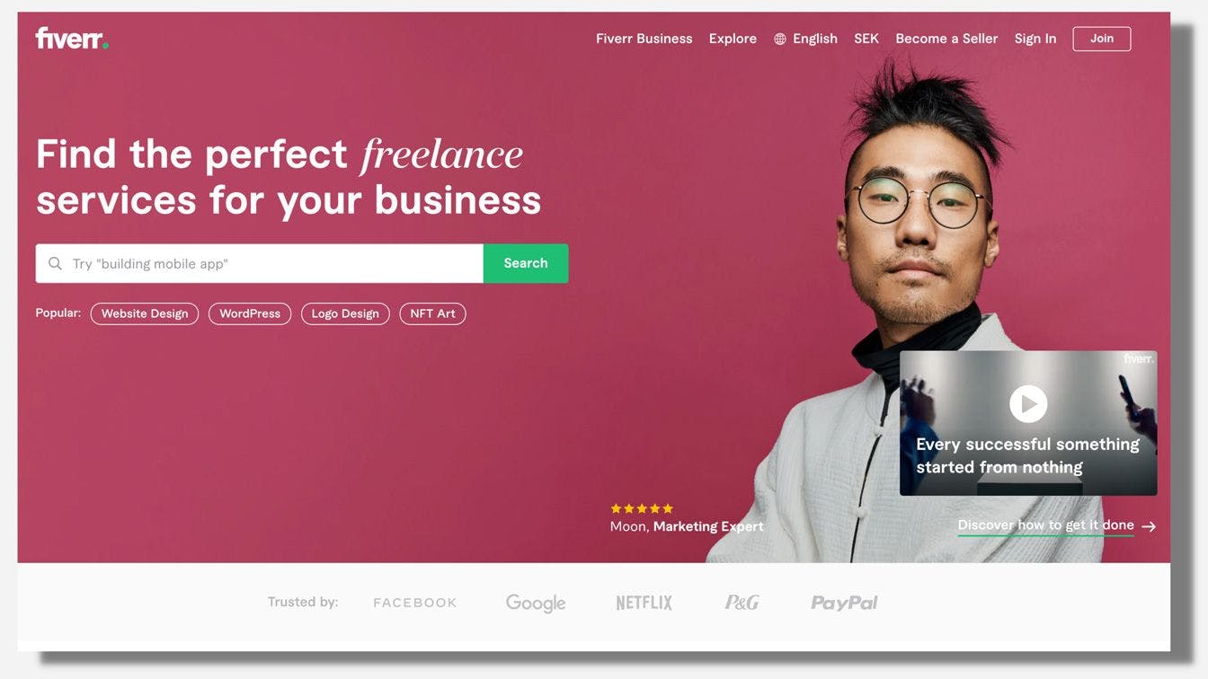Screenshot of Fiverr homepage with pink and black background and man in glasses on web