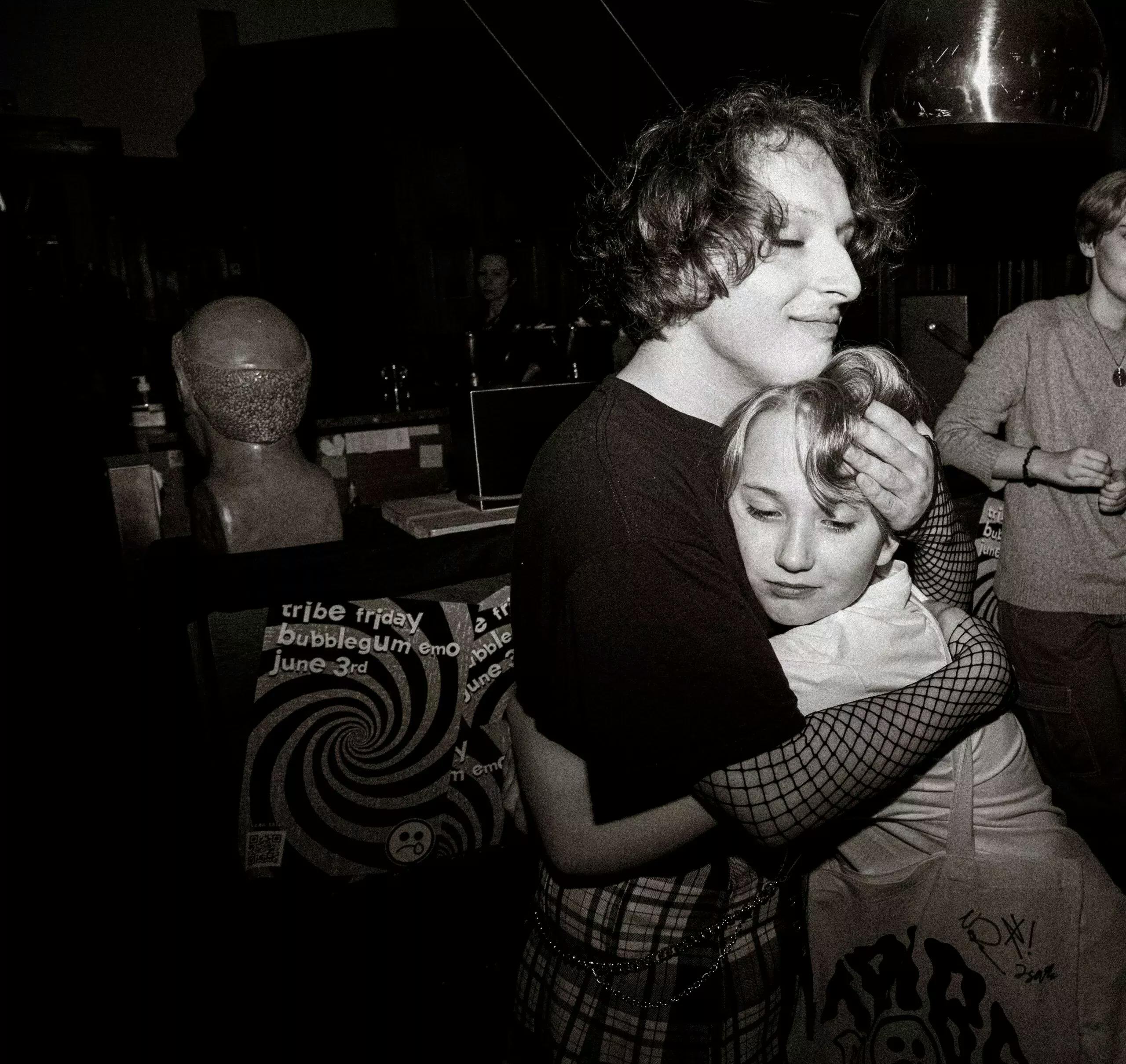 Tribe Friday at their bubblegum emo LP launch party hugging one of their superfans.