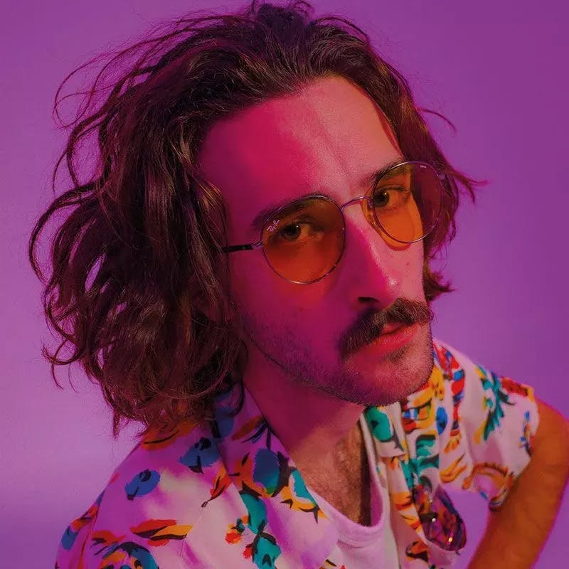 Portrait of music artist Brooksie, against a bright purple background.